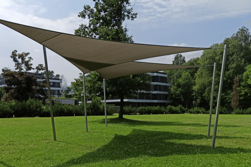 Napvitorla játszótér árnyékolás 6 Modern parkos terület árnyékolása szürke napvitorlával, acél oszlopokra kifeszítve